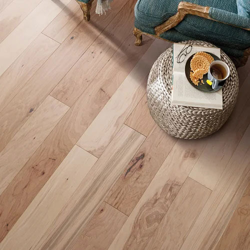 Round wooden table with woven basket centerpiece on light natural hardwood flooring.